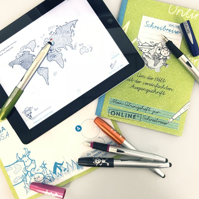 Verschiedene Schreiblernfüller liegen auf verschiedenen Heften und einem Tablet.