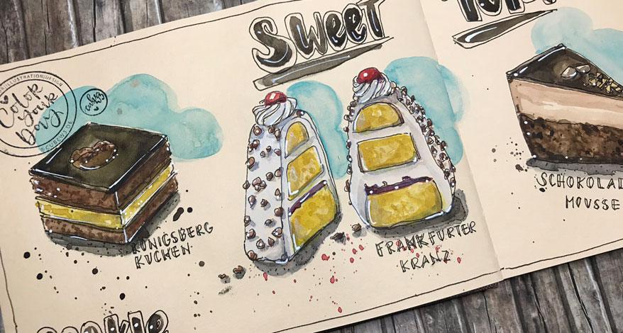 In das Toned Watercolour Book von Hahnemühle wurden verschiedene Kuchen mit Aquarellfarbe gemalt. Das Buch liegt auf einem Holzboden.