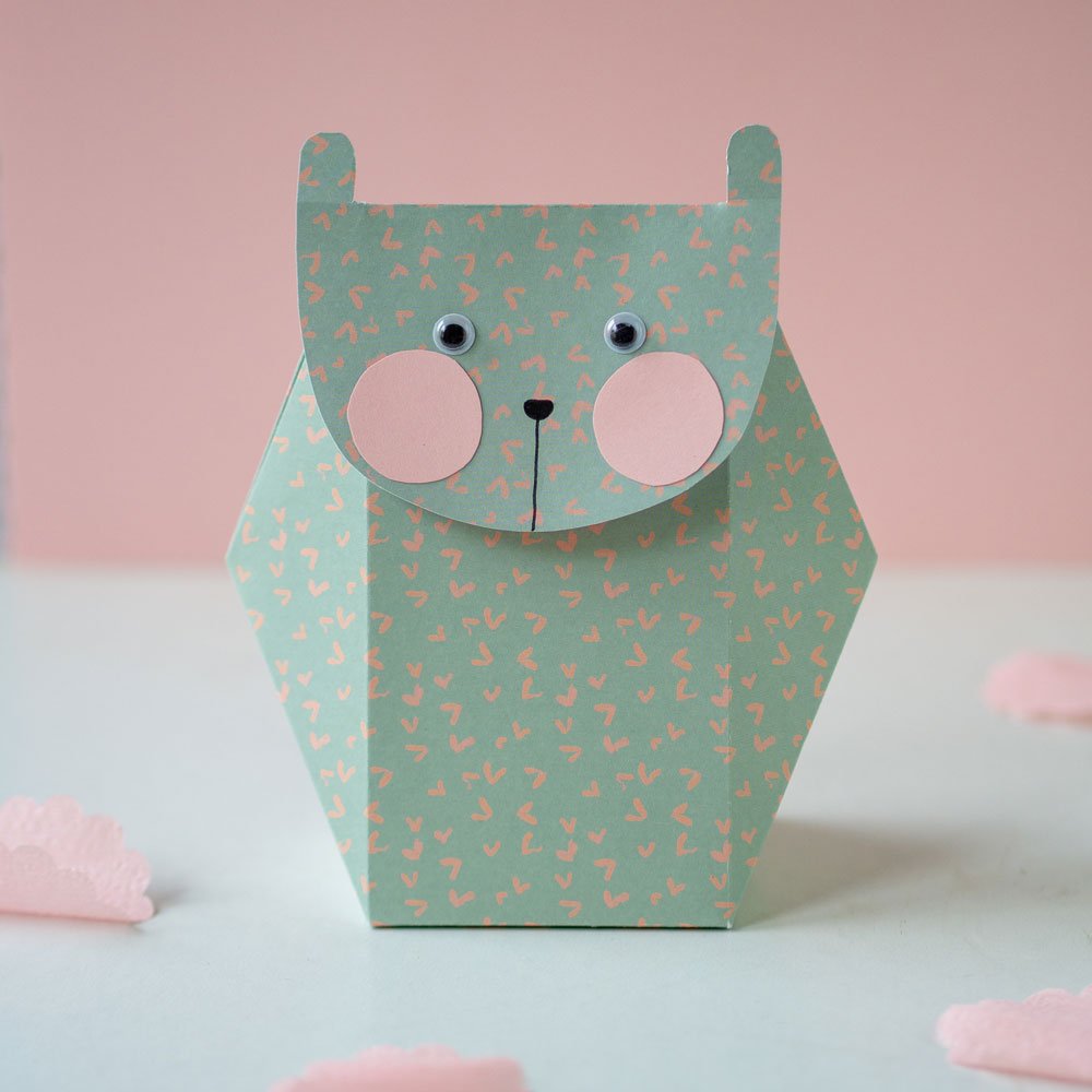 Selbstgebastelte Geschenkschachtel aus grünem Papier im Form einer Katze.