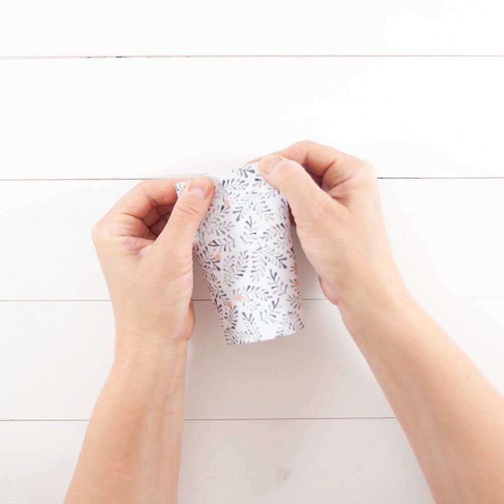 Zwei Hände drücken die kurze Seite der Papierrolle zusammen.