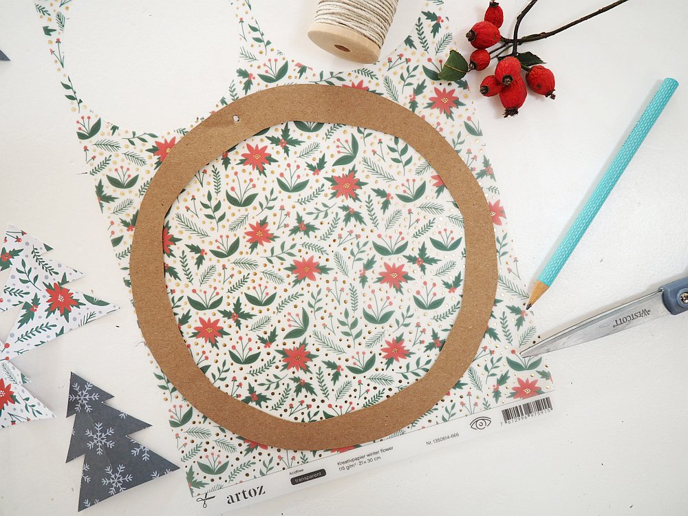 Weihnachtspapier, darauf ein Kreis aus Kraftpapier, Bastelmaterial drumherum