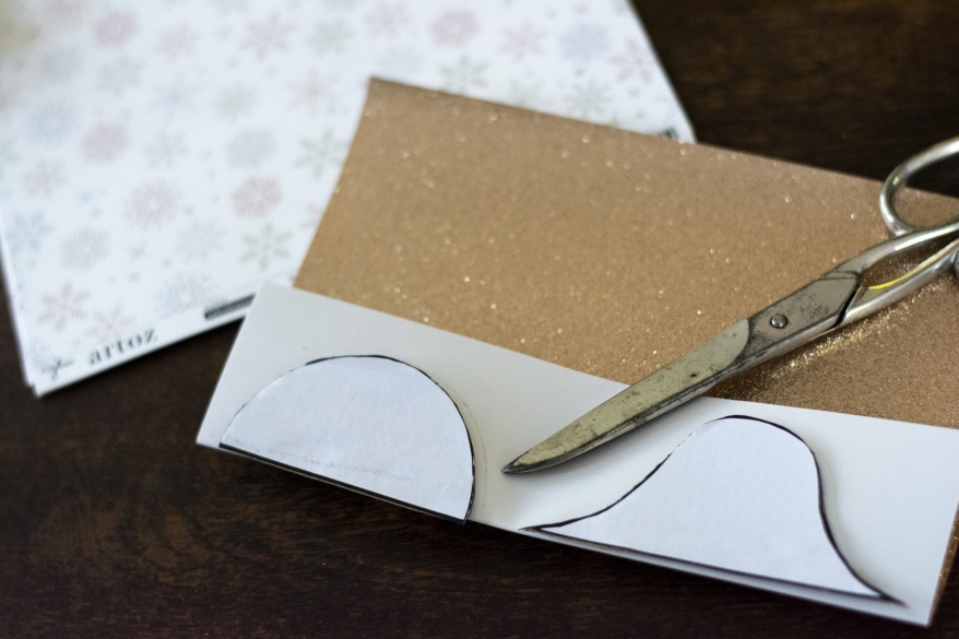 Glitzerkarton in Gold mit Schutzfolie auf der Rückseite. Darauf liegt eine Schere.