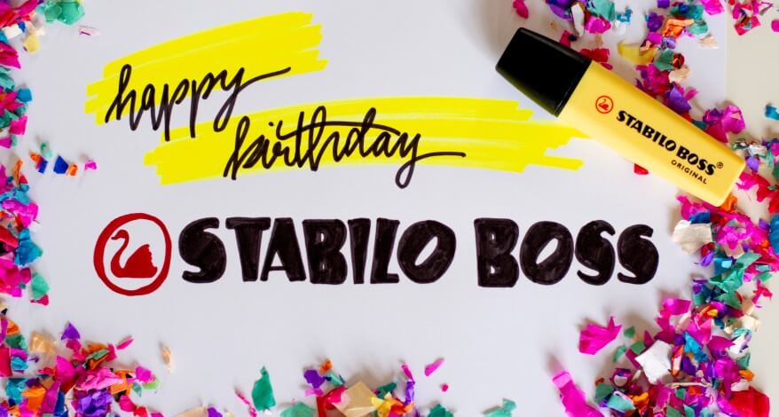 Auf einem Blatt steht "Happy Birthdas Satbilo Boss". Es liegt ein gelber Textmarker daneben und buntes Konfetti liegt auf dem Blatt verteilt.