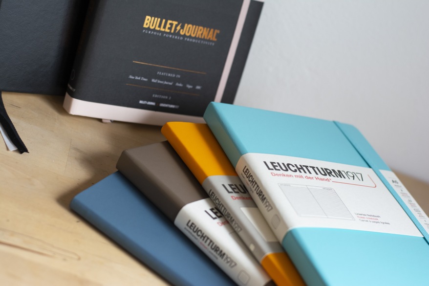 Bunte Leuchtturm1917-Notizbücher und Bullet Journal auf Holztisch