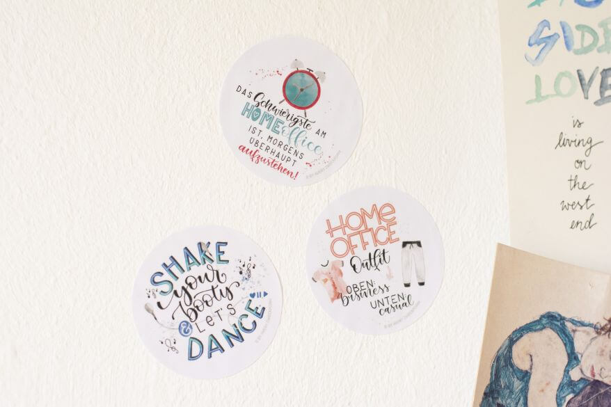 Drei runde Aufkleber von Avery Zweckform kleben an der Wand. Sie sind beschriftet mit Motivationssprüchen für das Homeoffice.