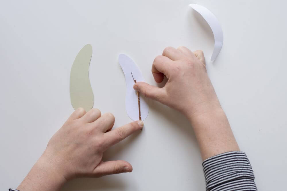 Bastelanleitung Do it yourself-Papierfedern. Schritt 4: Büroklammer mit Maskingtape in selbstklebenden Motivkarton einlegen.