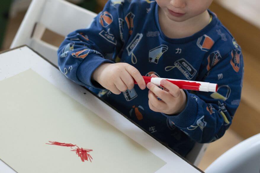 Ein Kind steckt die Kappe eines Filzstiftes aus der Kreativfabrik von Pelikan auf den Stift.