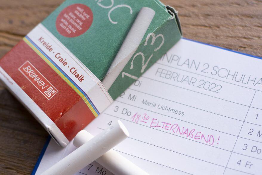 Auf einem aufgeschlagenen Terminkalender liegt weiße Tagelkreide von Brunnen.