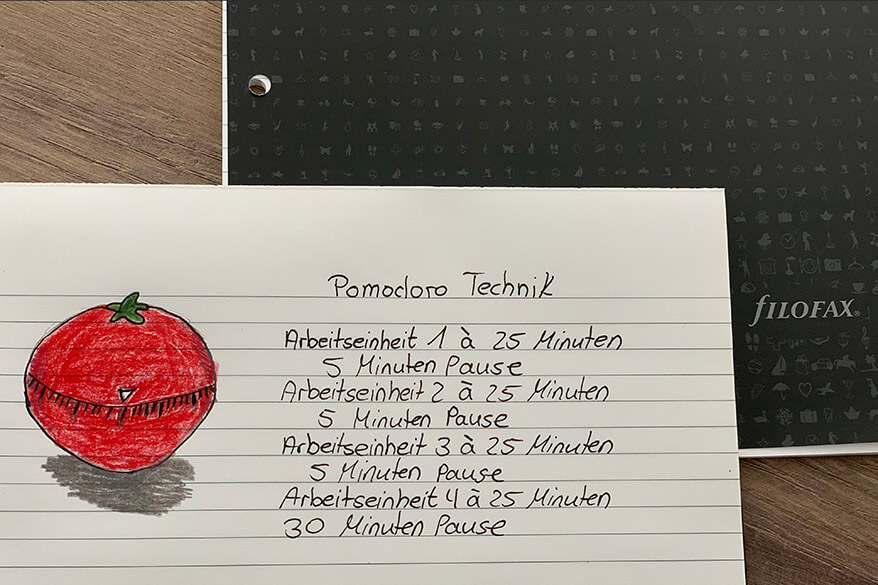 Auf einem Notizblock der Marke Filofax ist das Prinzip der Pomodoro-Technik geschrieben.