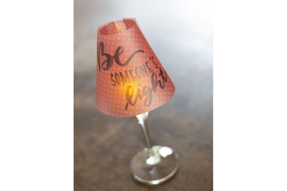 Roter selbstgebastelter und beletterter Lampenschirm auf einem Weinglas.