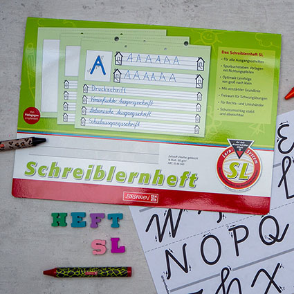 Auf einem hellen Untergrund liegt ein Schreiblernheft der Marke Brunnen mit einem Vorlagenbogen für die vereinfachte Ausgangsschrift. Neben dem Heft wurde mit bunten Radiergummi-Buchstaben "Heft SL" geschrieben. Eine rote Wachsmalkreide liegt darunter. Foto: Johanna Rundel