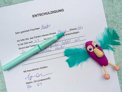 Auf einem türkisfarbenen Untergrund liegt ein ausgefüllter Ausdruck einer Entschuldigung für die Schule. Auf dem Dokument liegt ein türkisfarbener Tintenroller und eine selbstgebastelte Figur aus lila Knete von Staedtler, Wackelaugen, Perlen und Federn. Foto: Johanna Rundel