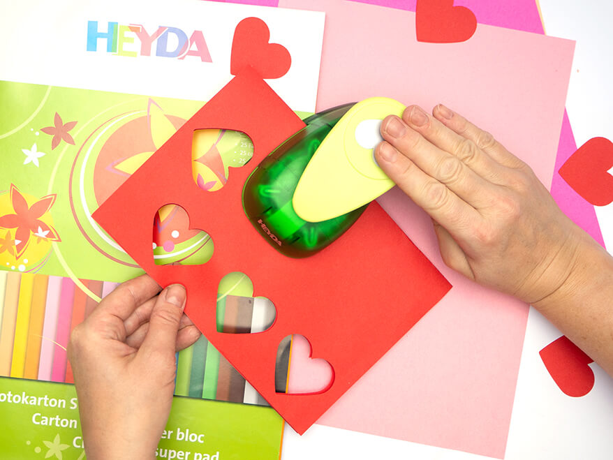 Mit einem Motivstanzer von Heyda werden Herzen aus farbigem Bastelkarton ausgestanzt. Foto: Johanna Rundel 