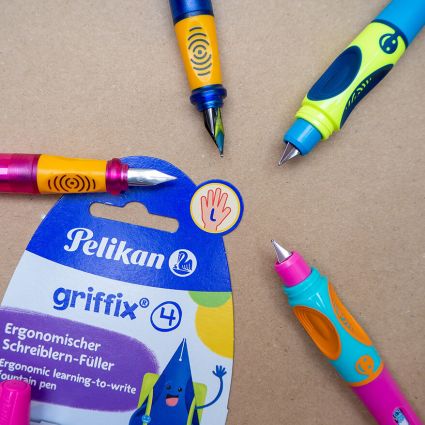 Auf einem braunen Packpapier liegt die Verpackung eines Griffix-Füllers für Linkshänder von Pelikan. Im Kreis darum liegen verschiedene Schreiblern- und Anfängerfüller in kindlichen Farben. Foto: Johanna Rundel