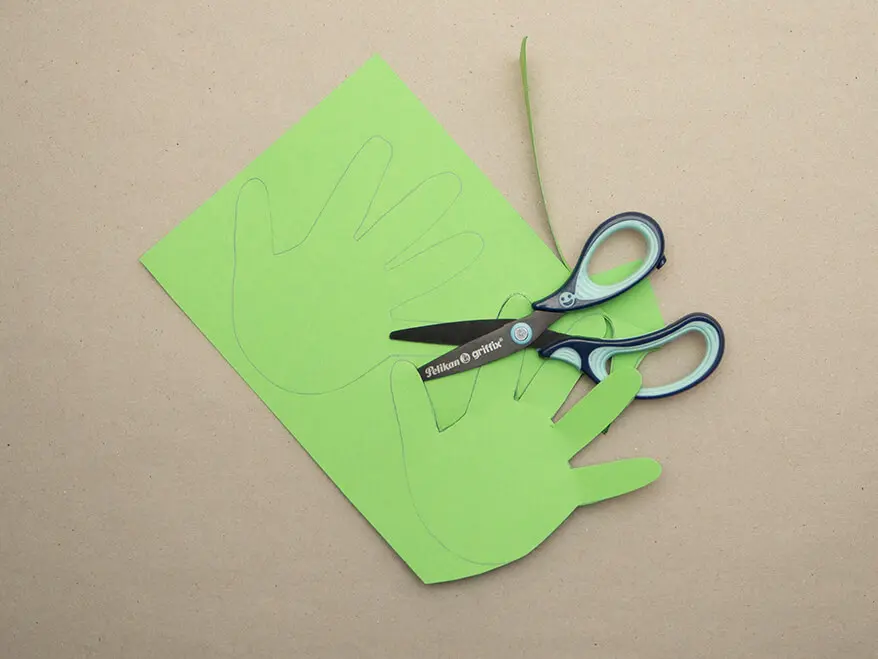 Die aufgemalten Umrisse zweier Hände werden mit einer griffix-Schere von Pelikan aus einem grünen Fotokarton von Herlitz ausgeschnitten. Foto: Johanna Rundel