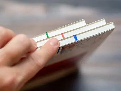 Jemand zeigt die Seite dreier Aquarellblöcke von Hahnemühle. Es sind verschiedenfarbige Striche zu sehen. Foto: Johanna Rundel