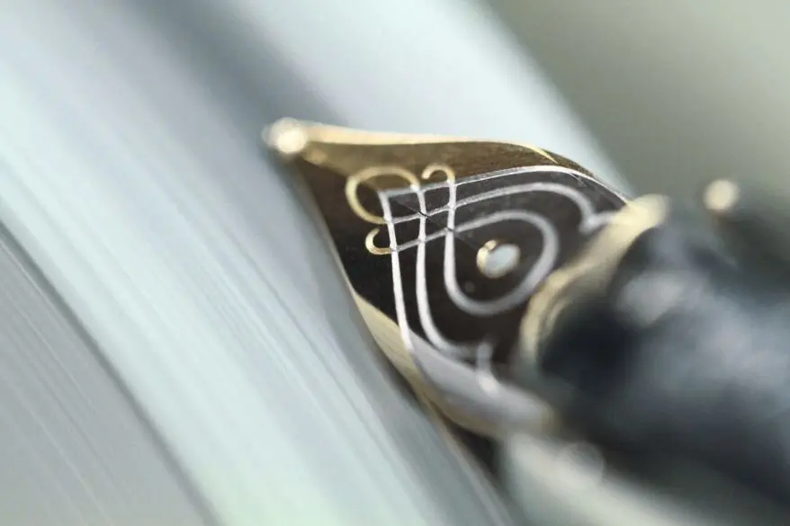 Detailaufnahme der Goldfeder eines Füllfederhalters von Pelikan an einer Schleifmaschine.