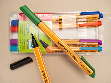 Ein Päckchen Faserschreiber in verschiedenen Farben von STABILO liegt auf einem grauen Untergrund. Zwei Stifte sind ausgepackt und liegen darauf. Foto: Johanna Rundel