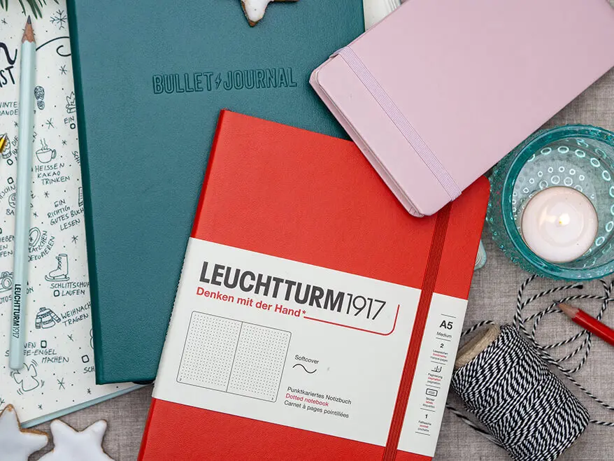 Drei Notizbücher von LEUCHTTURM1917 liegen übereinander auf einem winterlich dekorierten Tisch. Foto: Johanna Rundel