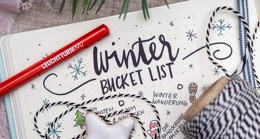 In einem Bullet Journal wurde eine Winter-Bucket-Liste angelegt. Auf der aufgeschlagenen Seite liegt ein roter Bleistift von LEUCHTTURM1917. Foto: Johanna Rundel