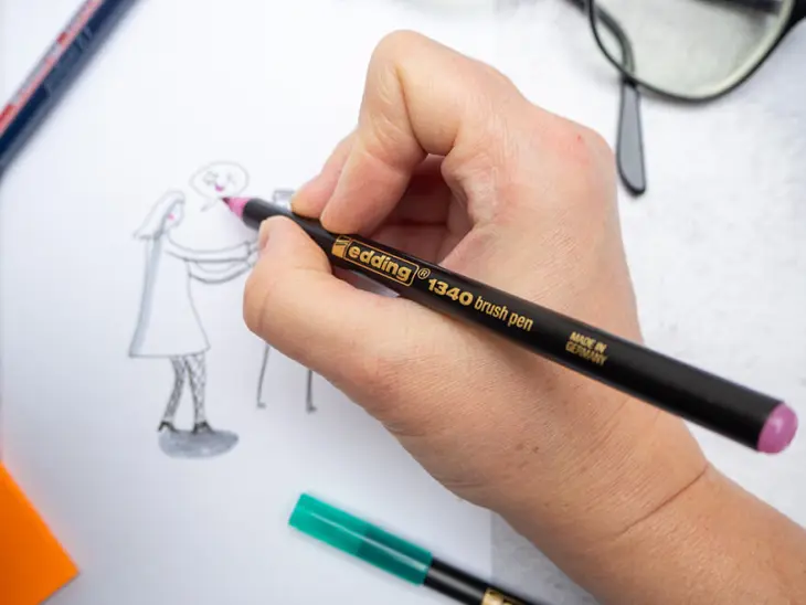 Jemand skizziert mit einem rosafarbenen Brushpen von edding eine Person auf ein weißes Blatt Papier. Foto: Johanna Rundel