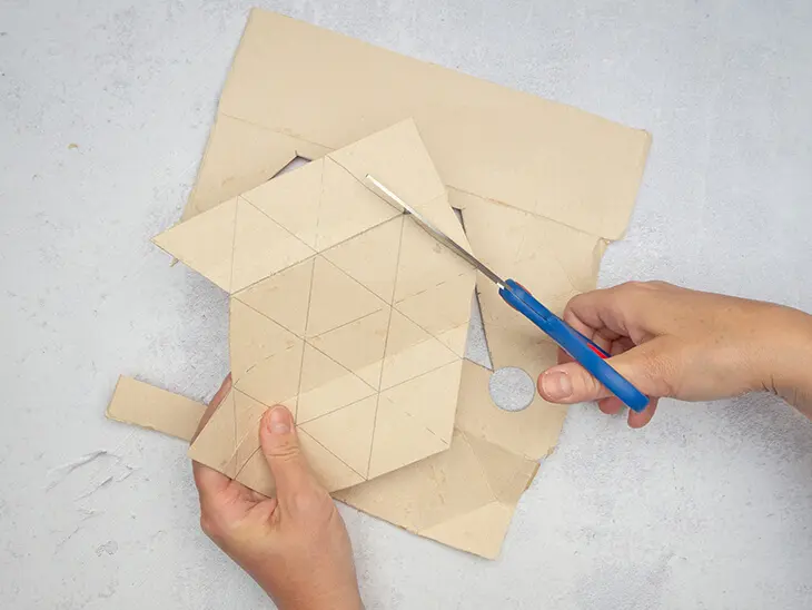Jemand schneidet mit einer Schere von KNORR prandell eine geometrische Form aus einer aufgefalteten Milchtüte.