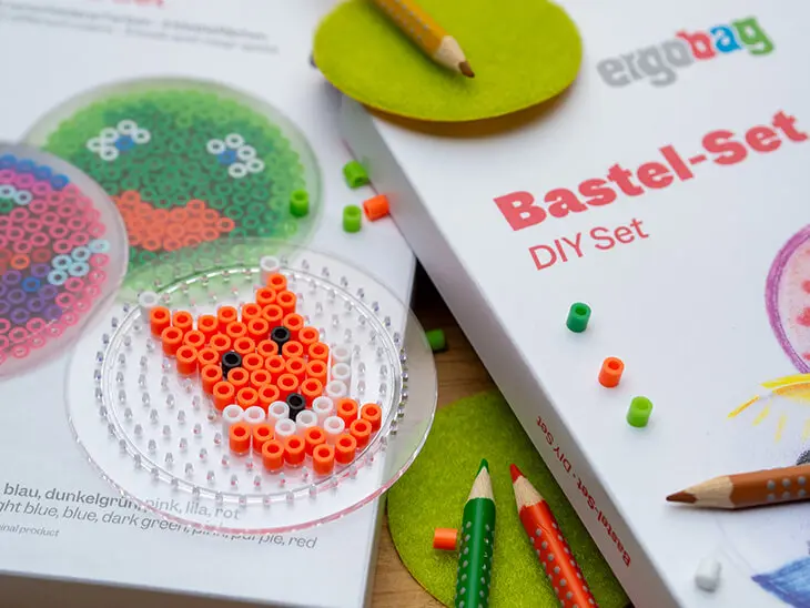 Ein rundes Bügelperlen-Steckbrett, auf dem ein Fuchs gelegt wurde, liegt auf der Verpackung eines Klettie-Bastelsets von ergobag. Foto: Johanna Rundel
