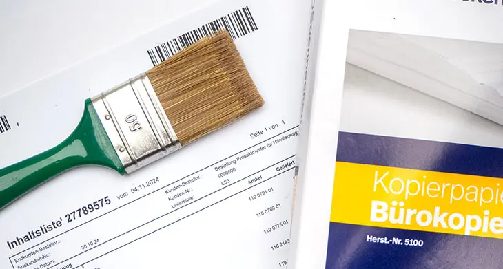 Ein Ausdruck liegt neben einem Paket Kopierpapier von Soennecken. Auf dem Ausdruck liegt ein breiter Pinsel. Foto: Johanna Rundel