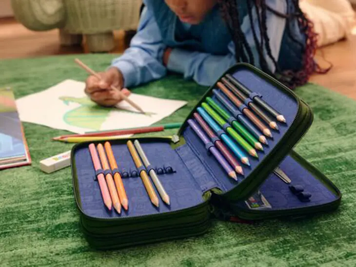 Ein Kind malt mit Stiften aus einem Mäppchen von ergobag ein Bild aus.