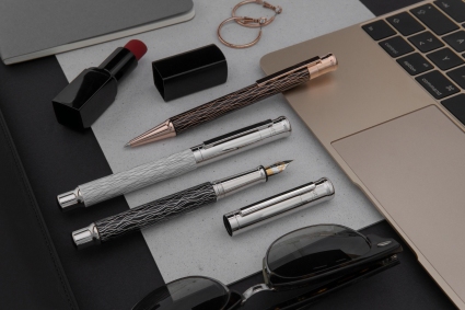 3 Schreibgeräte der Linie design04 von Otto Hutt liegen neben einem Laptop, Sonnenbrille und Lippenstift auf dem Tisch.