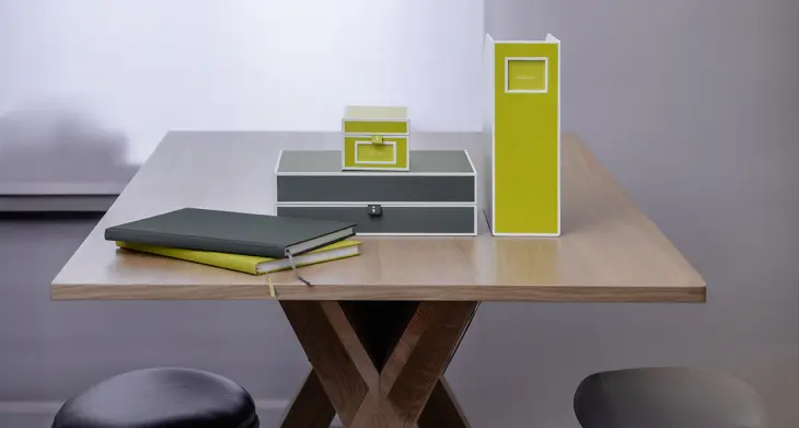 Auf einem Schreibtisch liegen Notizbücher, Boxen und ein Stehsammler von Semikolon.