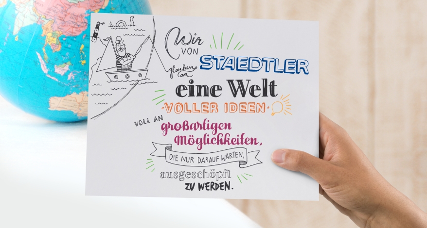 Eine bunt geletterte Karte wird in die Kamera gehalten, im Hintergrund ein Ausschnitt eines Globus.