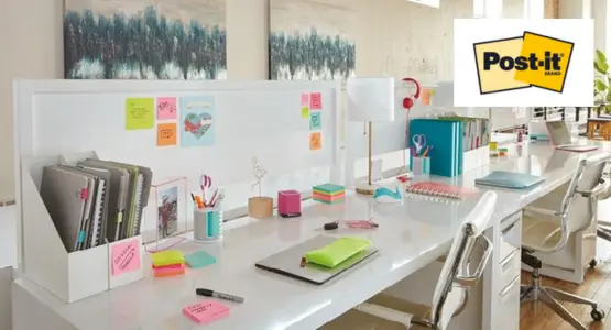 Auf einem weißen Schreibtisch liegen viele Post-it Haftnotizen und weiterer Bürobedarf.