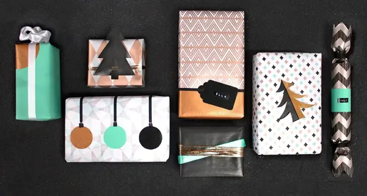 Auf einem schwarzen Untergrund liegen Weihnachtsgeschenke in unterschiedlicher Form und Größe. Sie sind kreativ mit Weihnachtspapiuer verpackt.