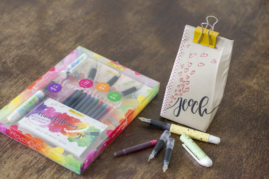  Bunte Brushpens von Online liegen neben gestalteter Geschenkbox.
