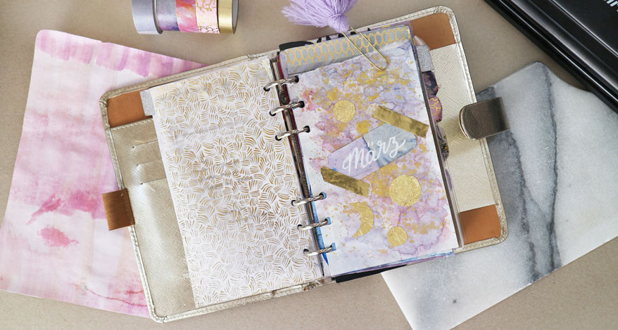 Flatlay eines Filofax Kalenders mit einem gestalteten Monatsdeckblatt. 