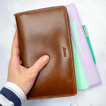 Jemand hält ein lila Notizbuch und einen dunkelbraunen Lederplaner von Filofax in die Kamera. Foto: Johanna Rundel