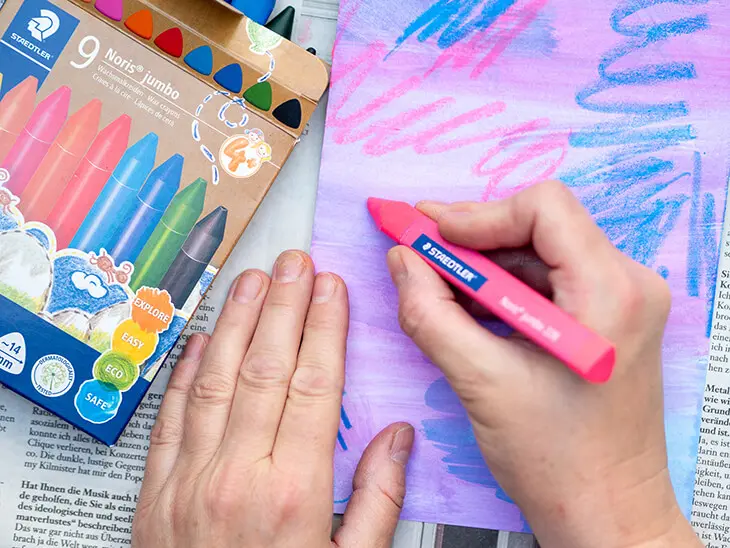Jemand malt mit einem Wachsmalstift von STAEDTLER Wasserfarbenbild an. Foto: Johanna Rundel