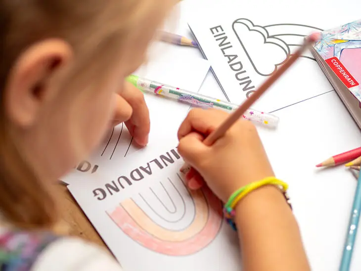 Ein Kind malt mit einem Buntstift von Coppenrath eine Einladungskarte zum Einhorn-Geburtstag aus. Foto: Johanna Rundel