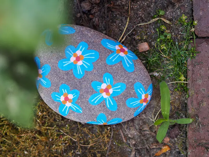 Auf einen Stein wurde mit POSCA-Markern kleine Blumen gemalt. Foto: Johanna Rundel