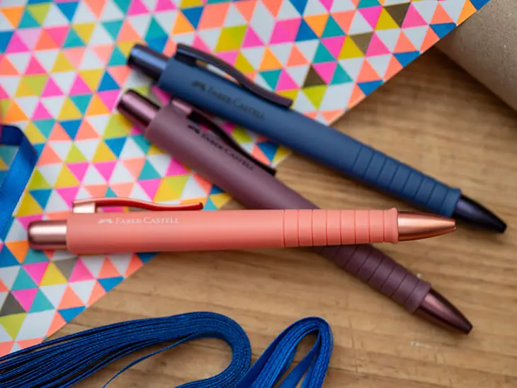 Drei bunte Kugelschreiber von Faber-Castell liegen auf Geschenkpapier. Foto: Johanna Rundel