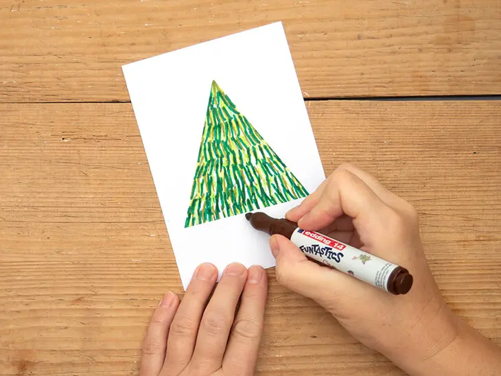 Jemand malt mit einem Fasermaler von edding einen Stamm unter einen Tannenbaum. Foto: Johanna Rundel