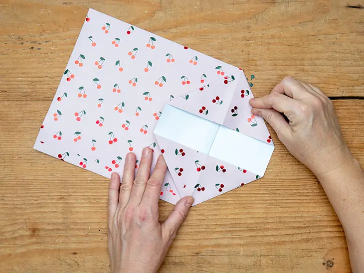 Jemand faltet eine Geschenktüte aus einem Geschenkpapier von STEWO. Foto: Johanna Rundel