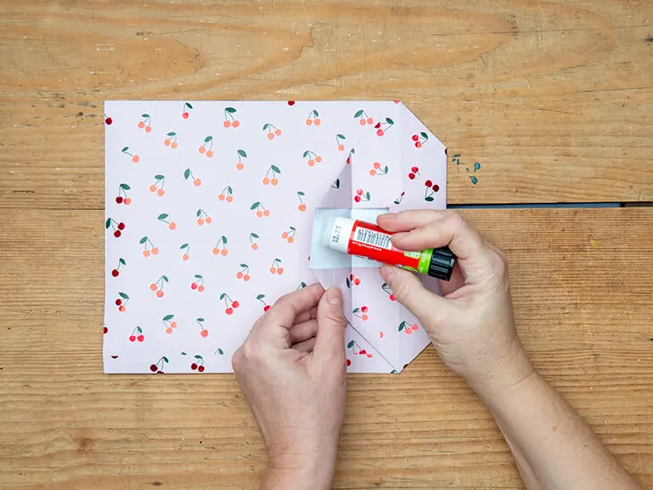 Jemand faltet eine Geschenktüte aus einem Geschenkpapier von STEWO. Foto: Johanna Rundel.