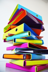 Viele übereinander gestapelte bunte Ordner und Ringbücher von PAGNA