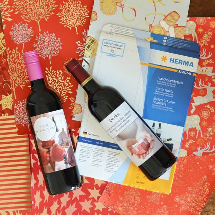 Zwei Weinflaschen mit Etiketten auf Weihnachtspapier und HERMA Etiketten.