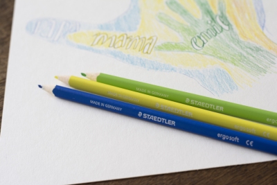 Zeichnung mit Händen und drei Staedtler-Buntstiften auf Tisch