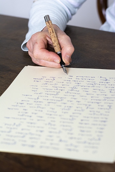 Hand schreibt mit Füller auf Briefpapier