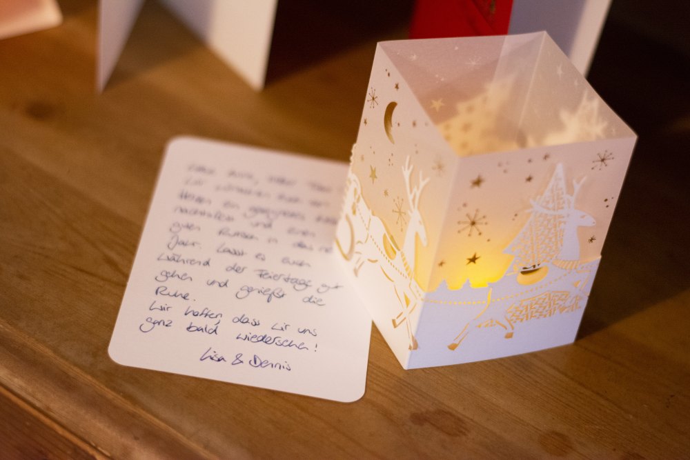 Weihnachtliches Windlicht mit Rentieren, daneben handgeschriebene Karte.