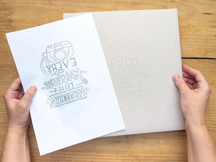Jemand nimmt eine Bleistiftvorlage eines Letterings von einem Fotoalbum-Cover ab. Der übertragene Abdruck der Vorlage ist darauf zu erkennen. Foto: Johanna Rundel
